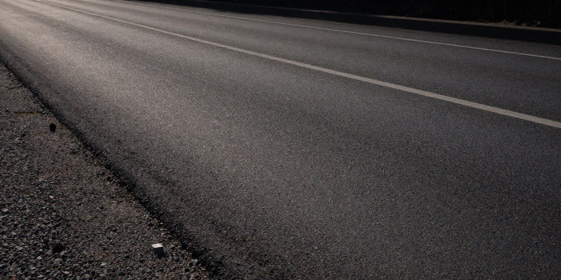 路肩に砂利が残る夕方の直線道路