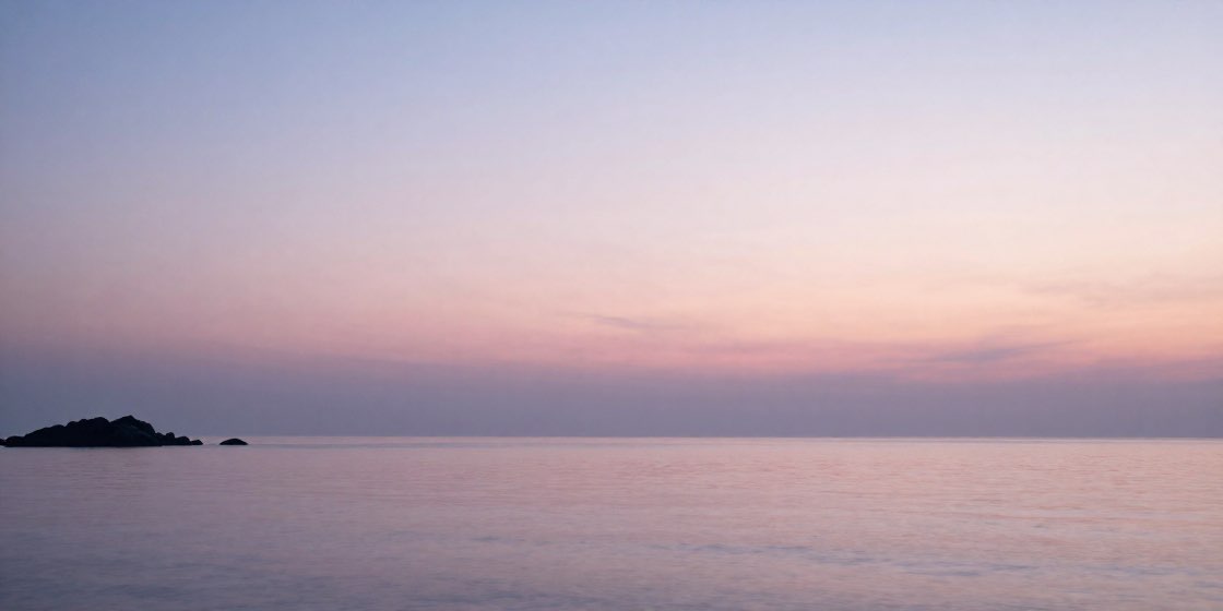 夕暮れの穏やかな海と遠くの岩影